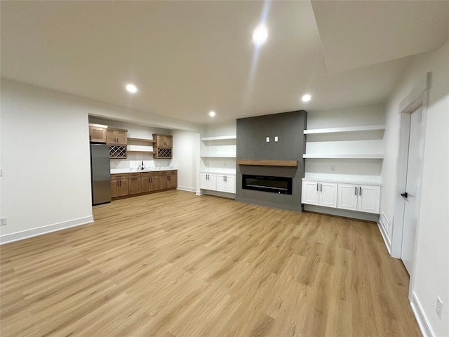 16332 Northpark Dr, Urbandale, IA 50323 - unfurnished living room featuring light wood-style flooring, a sink, baseboards, recessed lighting, and a large fireplace