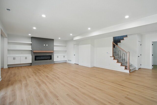16332 Northpark Dr, Urbandale, IA 50323 - unfurnished living room with stairway, light wood-style flooring, recessed lighting, baseboards, and a large fireplace