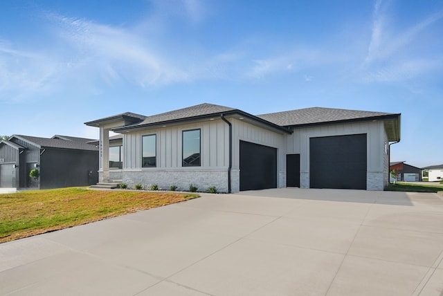 16332 Northpark Dr, Urbandale, IA 50323 - view of front of property with an attached garage, concrete driveway, a shingled roof, a front lawn, and stone siding