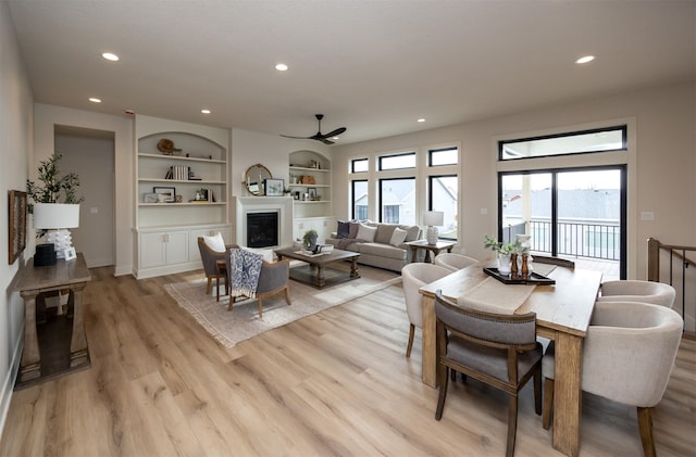6204 Aspen Dr, West Des Moines, IA 50266 - dining space featuring a glass covered fireplace, ceiling fan, recessed lighting, light wood finished floors, and built in features