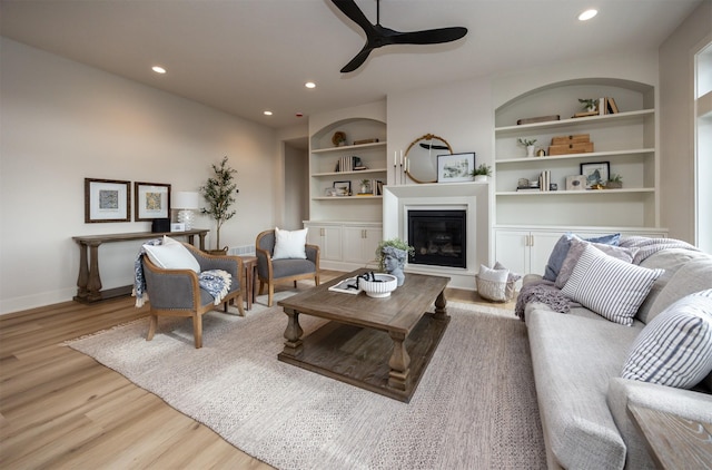6204 Aspen Dr, West Des Moines, IA 50266 - living area with a ceiling fan, built in features, light wood-style flooring, a glass covered fireplace, and recessed lighting