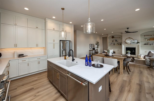 6204 Aspen Dr, West Des Moines, IA 50266 - kitchen featuring appliances with stainless steel finishes, a sink, ceiling fan, a fireplace, and light wood finished floors