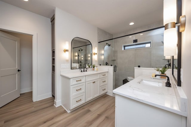 6204 Aspen Dr, West Des Moines, IA 50266 - full bathroom with two vanities, a shower stall, wood finished floors, recessed lighting, and baseboards