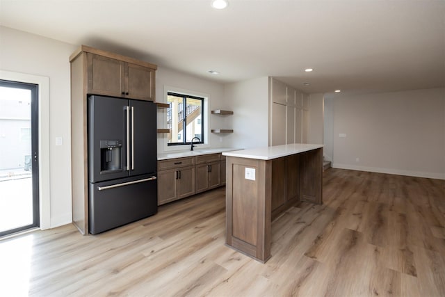 6204 Aspen Dr, West Des Moines, IA 50266 - kitchen featuring high end black refrigerator, light wood-style flooring, a kitchen island, light countertops, and recessed lighting