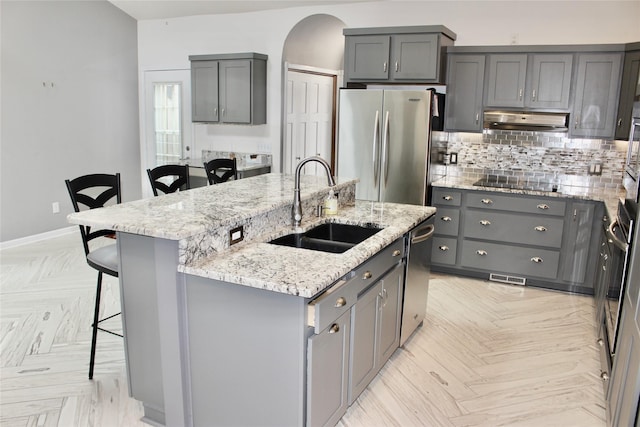 730 Kitterman Cir, Norwalk, IA 50211 - kitchen with stainless steel appliances, a sink, gray cabinets, under cabinet range hood, and arched walkways