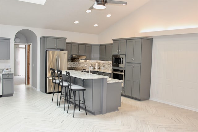 730 Kitterman Cir, Norwalk, IA 50211 - kitchen featuring stainless steel appliances, decorative backsplash, a ceiling fan, baseboards, and light stone counters
