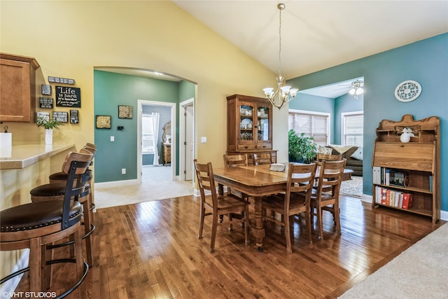 703 NE 46th Ct, Ankeny, IA 50021 - dining area featuring dark wood-style flooring, a chandelier, arched walkways, baseboards, and high vaulted ceiling