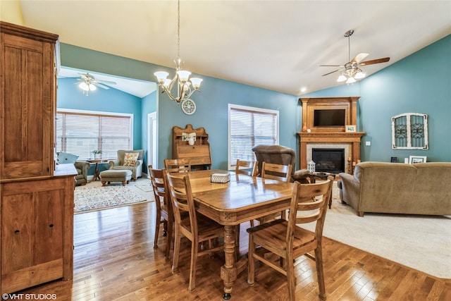 703 NE 46th Ct, Ankeny, IA 50021 - dining room featuring lofted ceiling, a ceiling fan, a glass covered fireplace, light wood-style flooring, and a chandelier