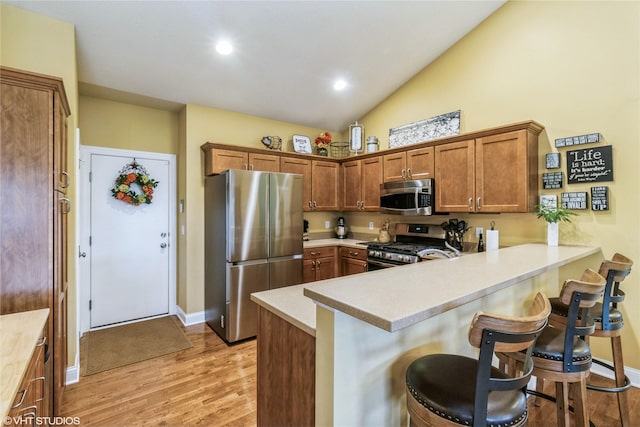 703 NE 46th Ct, Ankeny, IA 50021 - kitchen with appliances with stainless steel finishes, a peninsula, light countertops, light wood-style floors, and a kitchen bar