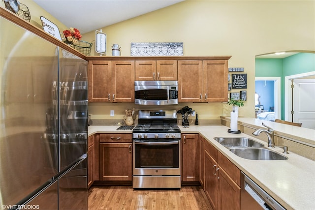 703 NE 46th Ct, Ankeny, IA 50021 - kitchen featuring appliances with stainless steel finishes, a sink, arched walkways, light countertops, and vaulted ceiling