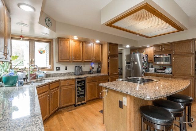 10490 Elmcrest Dr, Clive, IA 50325 - kitchen featuring appliances with stainless steel finishes, wine cooler, a sink, brown cabinets, and light wood finished floors