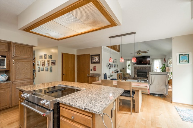 10490 Elmcrest Dr, Clive, IA 50325 - kitchen with stainless steel appliances, light wood-style flooring, a brick fireplace, a center island, and open floor plan