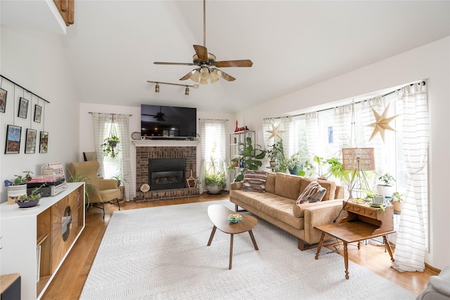 10490 Elmcrest Dr, Clive, IA 50325 - living area featuring vaulted ceiling, a fireplace, light wood-style floors, and a ceiling fan