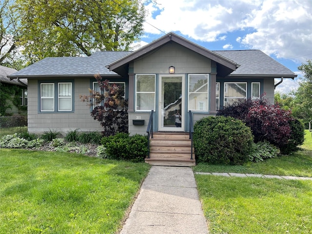 311 W 8th St S, Newton, IA 50208 - bungalow-style house featuring a shingled roof, a front lawn, a sunroom, and entry steps