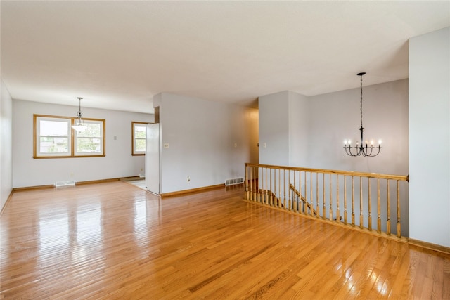 602 SE 7th St, Ankeny, IA 50021 - empty room with light wood-type flooring, a chandelier, and baseboards
