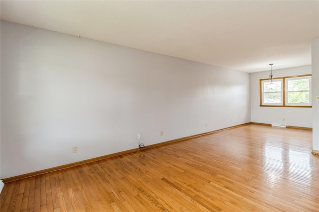 602 SE 7th St, Ankeny, IA 50021 - empty room featuring light wood-style floors, baseboards, and a chandelier
