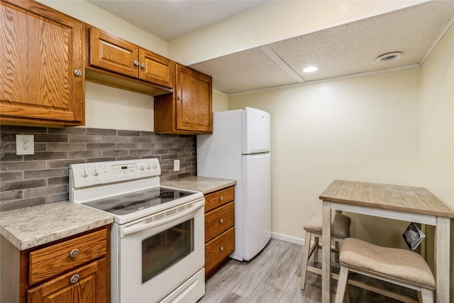 602 SE 7th St, Ankeny, IA 50021 - kitchen featuring white appliances, brown cabinets, light wood-style floors, light countertops, and decorative backsplash