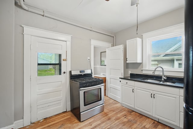 3114 School St, Des Moines, IA 50311 - kitchen with gas range, a sink, light wood-type flooring, white cabinets, and dark countertops