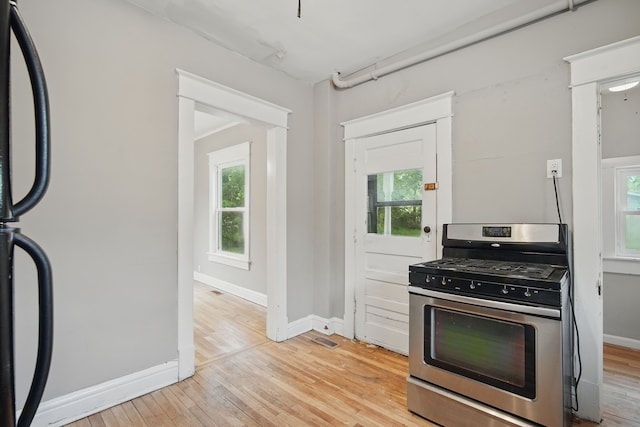 3114 School St, Des Moines, IA 50311 - kitchen with stainless steel gas stove, light wood finished floors, and baseboards