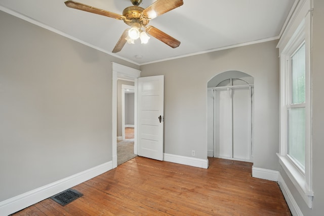3114 School St, Des Moines, IA 50311 - unfurnished room with arched walkways, ornamental molding, baseboards, light wood-type flooring, and a ceiling fan