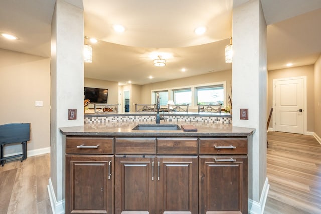 2315 14th St SW, Altoona, IA 50009 - kitchen with dark stone counters, a sink, light wood finished floors, dark brown cabinetry, and baseboards