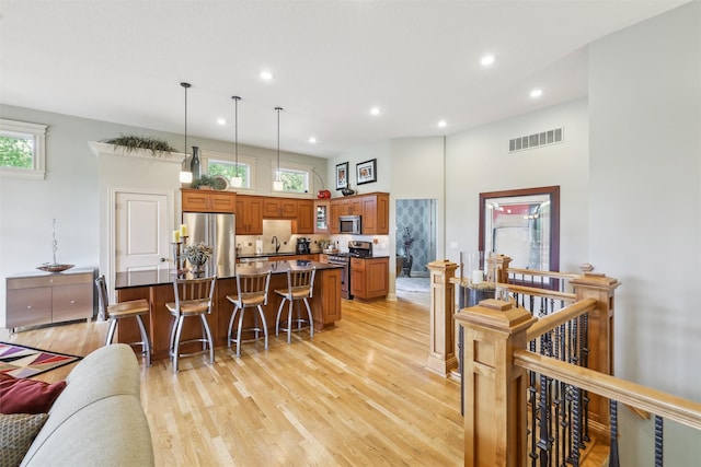 1176 Glen Oaks Dr, West Des Moines, IA 50266 - kitchen with stainless steel appliances, light wood-style floors, a center island, dark countertops, and plenty of natural light