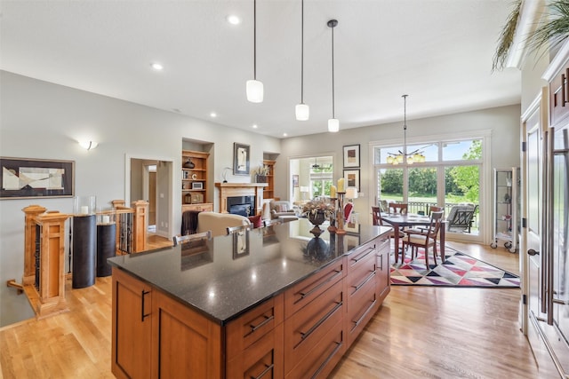 1176 Glen Oaks Dr, West Des Moines, IA 50266 - kitchen featuring light wood-type flooring, a center island, a glass covered fireplace, recessed lighting, and brown cabinets