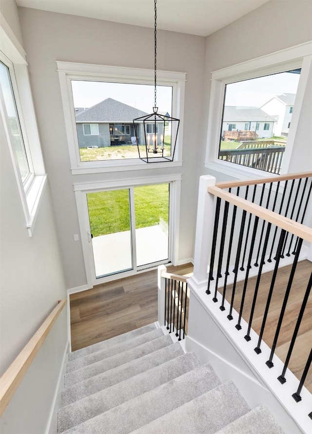 3309 NW Reinhart Dr, Ankeny, IA 50023 - stairs featuring a chandelier, wood finished floors, and baseboards