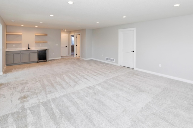 3309 NW Reinhart Dr, Ankeny, IA 50023 - unfurnished living room featuring beverage cooler, recessed lighting, wet bar, light carpet, and baseboards