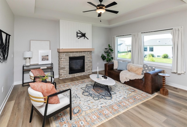 3309 NW Reinhart Dr, Ankeny, IA 50023 - living room with a raised ceiling, wood finished floors, baseboards, a ceiling fan, and a glass covered fireplace
