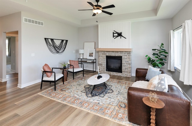 3309 NW Reinhart Dr, Ankeny, IA 50023 - living area featuring wood finished floors, ceiling fan, a tray ceiling, and baseboards