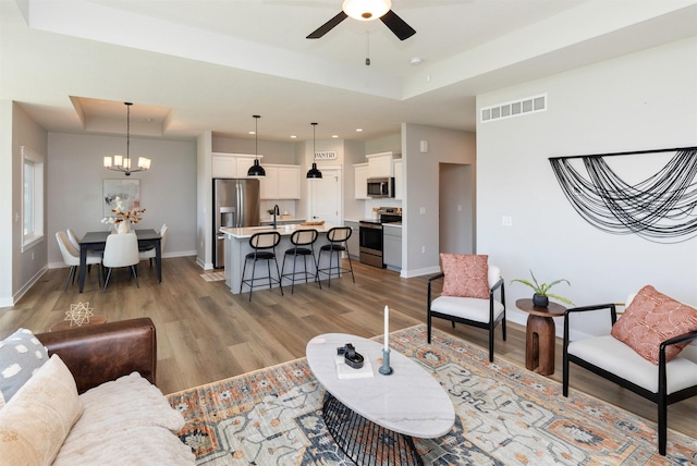 3309 NW Reinhart Dr, Ankeny, IA 50023 - living room with a tray ceiling, light wood-style flooring, ceiling fan, a chandelier, and recessed lighting