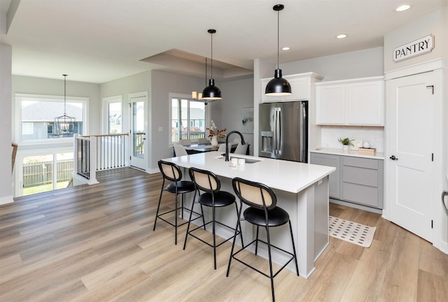 3309 NW Reinhart Dr, Ankeny, IA 50023 - kitchen featuring stainless steel refrigerator with ice dispenser, a sink, light wood finished floors, a center island with sink, and a breakfast bar area