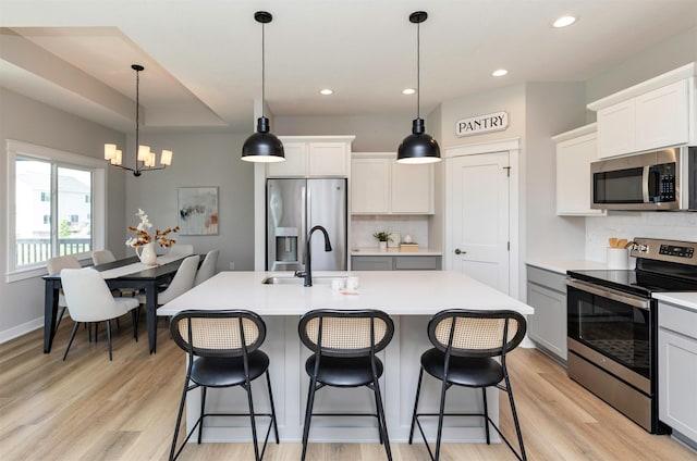 3309 NW Reinhart Dr, Ankeny, IA 50023 - kitchen featuring appliances with stainless steel finishes, a sink, a chandelier, tasteful backsplash, and light wood-type flooring