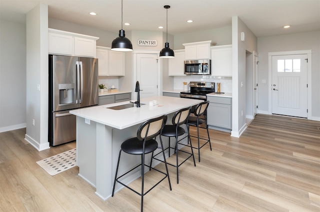 3309 NW Reinhart Dr, Ankeny, IA 50023 - kitchen featuring appliances with stainless steel finishes, a sink, tasteful backsplash, light wood-style flooring, and light countertops