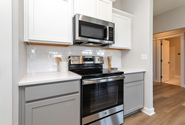 3309 NW Reinhart Dr, Ankeny, IA 50023 - kitchen featuring appliances with stainless steel finishes, light wood-type flooring, decorative backsplash, and light countertops