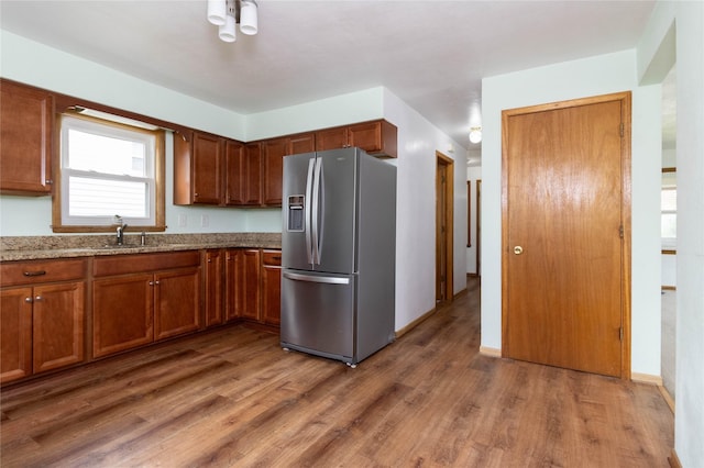 221 W Division St, Colfax, IA 50054 - kitchen with stainless steel fridge, wood finished floors, light stone countertops, brown cabinets, and a sink