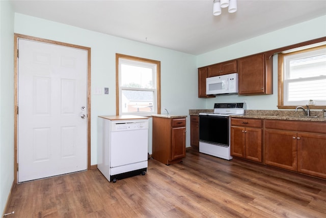 221 W Division St, Colfax, IA 50054 - kitchen with white appliances, wood finished floors, a sink, and brown cabinetry