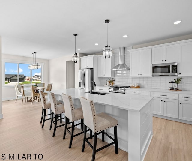 4641 179th St, Urbandale, IA 50323 - kitchen featuring a sink, appliances with stainless steel finishes, wall chimney range hood, tasteful backsplash, and a kitchen island with sink