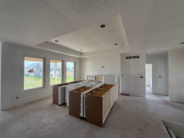 4641 179th St, Urbandale, IA 50323 - kitchen featuring a textured ceiling, a raised ceiling, and a kitchen island