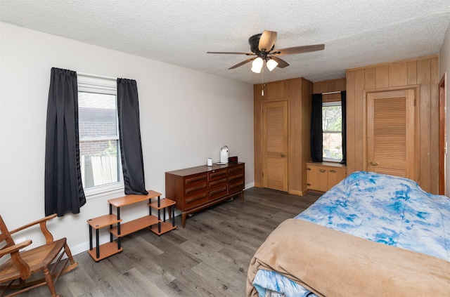936 15th St, West Des Moines, IA 50265 - bedroom with wood finished floors, a textured ceiling, baseboards, a ceiling fan, and wood walls