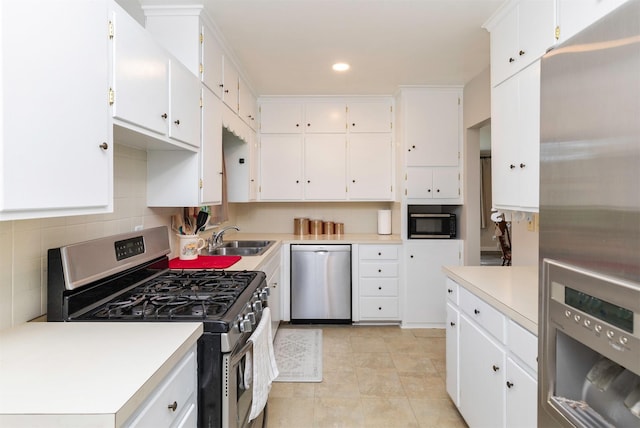 936 15th St, West Des Moines, IA 50265 - kitchen with appliances with stainless steel finishes, a sink, light countertops, white cabinets, and tasteful backsplash
