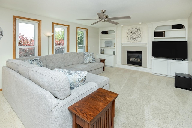 5525 SE 29th Ct, Des Moines, IA 50320 - living room featuring ceiling fan, built in shelves, a glass covered fireplace, and light carpet