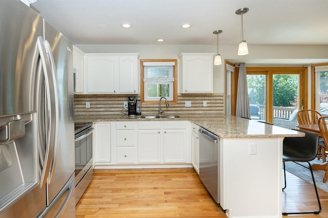 5525 SE 29th Ct, Des Moines, IA 50320 - kitchen featuring appliances with stainless steel finishes, a sink, a peninsula, decorative backsplash, and white cabinets