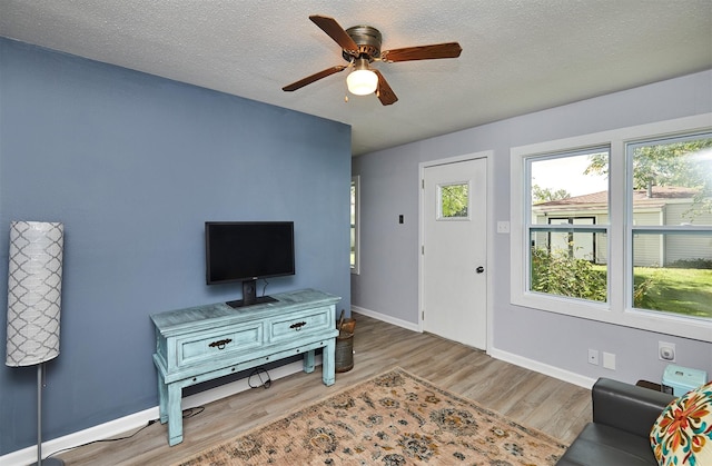 623 W Front St, Stuart, IA 50250 - living room featuring light wood-type flooring, a ceiling fan, baseboards, and a textured ceiling