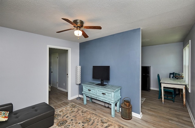 623 W Front St, Stuart, IA 50250 - living area with a ceiling fan, wood finished floors, baseboards, and a textured ceiling