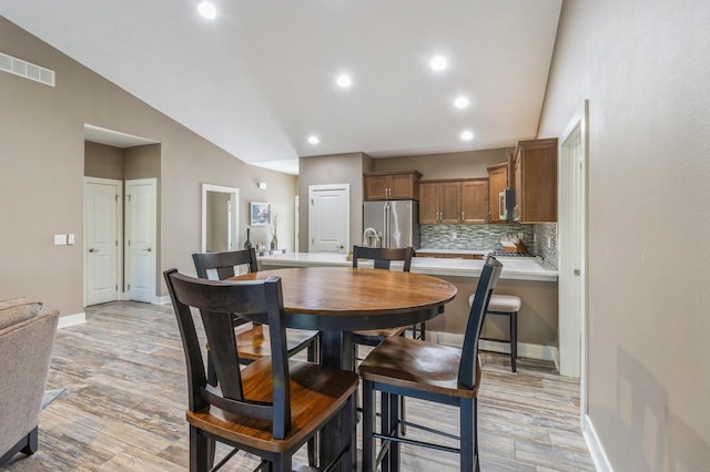 5645 Prairie Grass Dr, Johnston, IA 50131 - dining room featuring light wood finished floors, lofted ceiling, baseboards, and recessed lighting