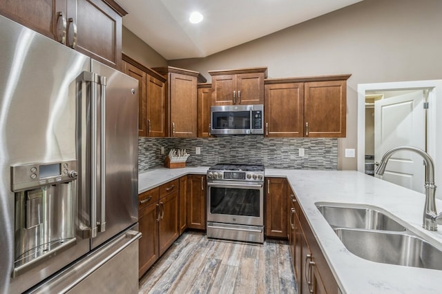 5645 Prairie Grass Dr, Johnston, IA 50131 - kitchen with appliances with stainless steel finishes, a sink, vaulted ceiling, tasteful backsplash, and light wood-style floors
