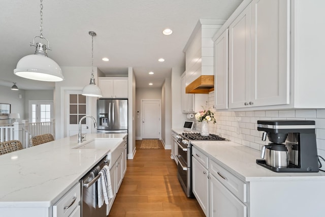 901 Cardinal Dr, Polk City, IA 50226 - kitchen with stainless steel appliances, a sink, white cabinets, decorative backsplash, and light wood finished floors