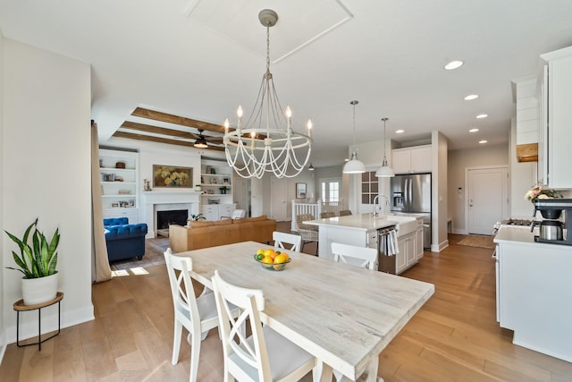 901 Cardinal Dr, Polk City, IA 50226 - dining space featuring a fireplace, light wood-style floors, a chandelier, recessed lighting, and built in features